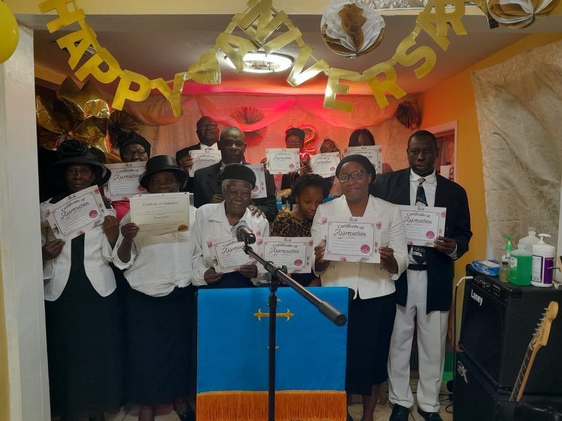 Members of the church holding certificates at the front of the sanctuary